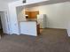 Open living room space featuring neutral carpet, with an adjacent kitchen and white appliances at 2019 Rancho Lake Dr # 102, Las Vegas, NV 89108