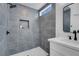 Modern bathroom features a gray-tiled shower with a niche, stylish fixtures, and white vanity at 2832 Sing Song Way, Las Vegas, NV 89106