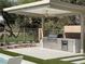 Covered outdoor kitchen featuring stainless steel appliances, a built-in grill, and a beverage fridge at 5 Clear Crossing Trl, Henderson, NV 89052
