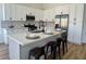 Bright kitchen features white cabinetry, stainless steel appliances, and a quartz countertop island with seating at 5600 Nimes Ave, Las Vegas, NV 89141