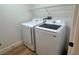 Convenient laundry room with side-by-side Samsung washer and dryer, wire shelving, and wood-look floors at 5600 Nimes Ave, Las Vegas, NV 89141