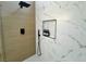 Close up on sleek shower featuring marble-look tiling, a niche with bath products, and dual shower heads at 5600 Nimes Ave, Las Vegas, NV 89141