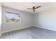 Well-lit bedroom with gray wood-look flooring, ceiling fan, and a window overlooking the yard at 5800 Auborn Ave, Las Vegas, NV 89108