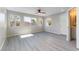 Bright bedroom featuring gray wood-look flooring, ceiling fan, and multiple windows with views of the yard at 5800 Auborn Ave, Las Vegas, NV 89108