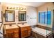 Bathroom featuring double sinks, tiled bathtub, and large vanity mirror with modern lighting at 6293 Pavestone Ln, Las Vegas, NV 89142