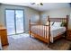 Cozy bedroom featuring a wooden bed frame, plush carpet, and sliding glass door to a balcony at 6293 Pavestone Ln, Las Vegas, NV 89142