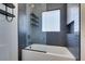 Modern tub with glass shower and unique dark shelving unit at 7132 Mission Hills Dr, Las Vegas, NV 89113