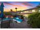 Beautiful backyard featuring a pool with a rock waterfall, lounge seating, and lush landscaping under a colorful sunset at 741 Canary Wharf Dr, Las Vegas, NV 89178