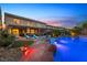 Expansive backyard featuring a sparkling pool with rock accents, covered patio, and meticulously manicured landscaping at 741 Canary Wharf Dr, Las Vegas, NV 89178