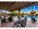 Covered patio with comfortable seating and outdoor dining area overlooking a gorgeous pool and lush landscaping, perfect for entertaining at 741 Canary Wharf Dr, Las Vegas, NV 89178