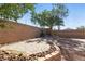 Cozy backyard with a paved patio, desert landscaping, block wall fence, and mature trees at 9004 Harbor Wind Ave, Las Vegas, NV 89178