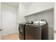 A clean laundry room with modern washer and dryer, featuring tile floors and shelving at 9004 Harbor Wind Ave, Las Vegas, NV 89178