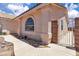 Side view of a lovely home with an arched window, stucco walls, and a pathway leading to a gated entrance at 918 Ambusher St, Henderson, NV 89014