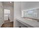 View of the hallway leading to the laundry room and a sunlit living area with large windows at 10325 Quartz Reef Ct, Las Vegas, NV 89141