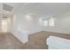 Open loft area with neutral carpet, white walls, and natural light from windows at 10325 Quartz Reef Ct, Las Vegas, NV 89141