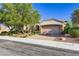 Charming single-story home with stone accents, mature trees, and a well-manicured front yard under a bright blue sky at 1897 Holdenville St, Henderson, NV 89052