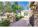 Charming front entrance with a brick pathway, decorative gate, and lush landscaping, leading to the home at 1897 Holdenville St, Henderson, NV 89052