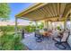 Outdoor covered patio area with stone pavers, manicured landscaping and a dining set at 1897 Holdenville St, Henderson, NV 89052