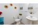 Bright powder room featuring a pedestal sink, toilet, mirror and decorative sunflowers at 210 Red Sandstone Ave, North Las Vegas, NV 89031