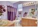 Well-lit bathroom featuring purple walls, vanity, tile floor, a large mirror, and a bathtub with shower at 4174 Cascada Piazza Ln, Las Vegas, NV 89135