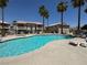 Large community pool with sun loungers and palm trees against blue sky at 435 Mesa Blvd # 202, Mesquite, NV 89027