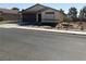 Tan one-story house with desert landscaping, a brown brick driveway, and a two-car garage at 5363 S Juneau St, Pahrump, NV 89061