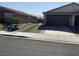 A desert landscaped front yard featuring a house with a two car garage and brown brick driveway at 5363 S Juneau St, Pahrump, NV 89061