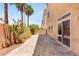 Home's exterior showcasing a private patio with brick pavers, a wall, and flowering vegetation with palm trees at 6014 Belvedere Canyon Ave, Las Vegas, NV 89139