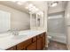 Well-lit bathroom with marble-style shower walls, a large mirror, a dark wood vanity and a white countertop at 6014 Belvedere Canyon Ave, Las Vegas, NV 89139