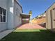 Inviting backyard features a covered patio, artificial turf, and a brick fire pit area, perfect for entertaining at 6063 Peach Orchard Rd, Las Vegas, NV 89142