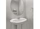 Well-lit half bathroom features a pedestal sink and round mirror at 6909 Toll Mountain St, North Las Vegas, NV 89086