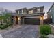 Charming two-story home with a brick driveway, arched entryway, and dark brown garage door at 6909 Toll Mountain St, North Las Vegas, NV 89086