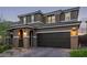 Charming two-story home with a brick driveway, arched entryway, and dark brown garage door at 6909 Toll Mountain St, North Las Vegas, NV 89086