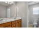 Well lit bathroom featuring a double sink vanity with a marble countertop and a toilet and shower at 9136 Cocowoods Pl, Las Vegas, NV 89148
