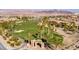 Scenic aerial view of Chimera Golf Club showcasing lush green fairways, palm trees, and mountain views in a vibrant community at 1004 Viale Placenza Pl, Henderson, NV 89011