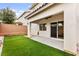 The backyard has lush artificial grass, a covered patio, and a secure sliding glass door for easy access at 10557 Bandera Mountain Ln, Las Vegas, NV 89166