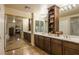Bathroom with a double sink vanity, large mirrors, and sliding doors leading to another room with fireplace at 11241 Pentland Downs St, Las Vegas, NV 89141