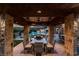 Covered outdoor dining area with stone columns overlooking pool and lush greenery, perfect for entertaining at 15 Golden Sunray Ln, Las Vegas, NV 89135
