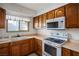 Functional kitchen with wooden cabinets, white appliances, and tile flooring offering a practical cooking space at 1716 Luning Dr, Las Vegas, NV 89106