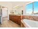 Bathroom with dual vanity, large mirror, soaking tub, and wooden cabinets at 1826 Monte Alban Dr, North Las Vegas, NV 89031