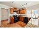 Kitchen with wood cabinets, tile floors, granite countertops, black appliances and modern lighting at 1826 Monte Alban Dr, North Las Vegas, NV 89031