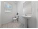 Minimalist half bathroom featuring a pedestal sink, toilet, and window with natural light at 2732 Roman Palm Rd, North Las Vegas, NV 89086