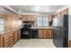 Bright kitchen featuring wood cabinets, granite counters, black appliances and a stainless steel refrigerator at 3471 Cape Cod Dr, Las Vegas, NV 89122