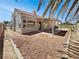 The backyard with desert landscaping, a covered patio, and mature palm trees at 3804 Wren Ct, North Las Vegas, NV 89032