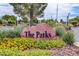 Entrance to 'The Parks' community featuring a stone sign surrounded by lush landscaping and colorful flowers at 406 River Glider Ave, North Las Vegas, NV 89084