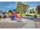 Community playground with a slide and play structure surrounded by lush landscaping and walking paths at 406 River Glider Ave, North Las Vegas, NV 89084