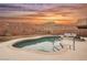 Sparkling pool with a spa, surrounded by a desert landscape and colorful sky at 47 Desert Sunflower Cir, Henderson, NV 89002