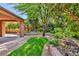 Backyard with covered patio, green artificial turf, rock features and lush landscaping at 5123 Southern Hills Ln, Las Vegas, NV 89113