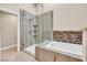 Elegant bathroom featuring a glass enclosed shower with shelving and a soaking tub with mosaic tile accents at 5123 Southern Hills Ln, Las Vegas, NV 89113