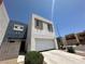 Modern two-story home features a two-car garage and neutral stucco, near a paved driveway and green shrubbery at 6450 Cinnamon Hazlenut St, North Las Vegas, NV 89084
